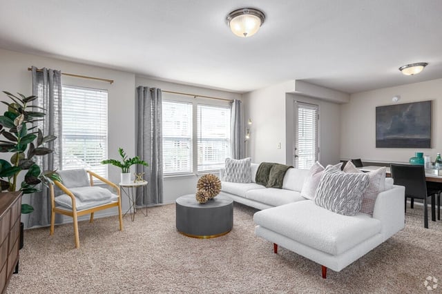 Living room with a white sectional sofa, accent chair, coffee table, and dining area.