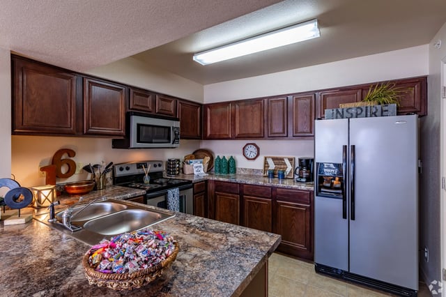 Kitchen with dark wood cabinets, stainless steel appliances, and a double sink.