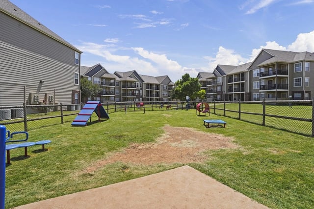 Grassy community courtyard with a playground and surrounding apartment buildings.