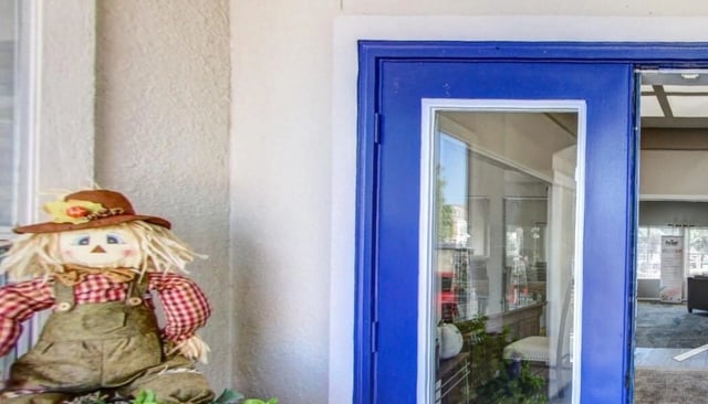 Scarecrow decoration outside a blue door entrance.