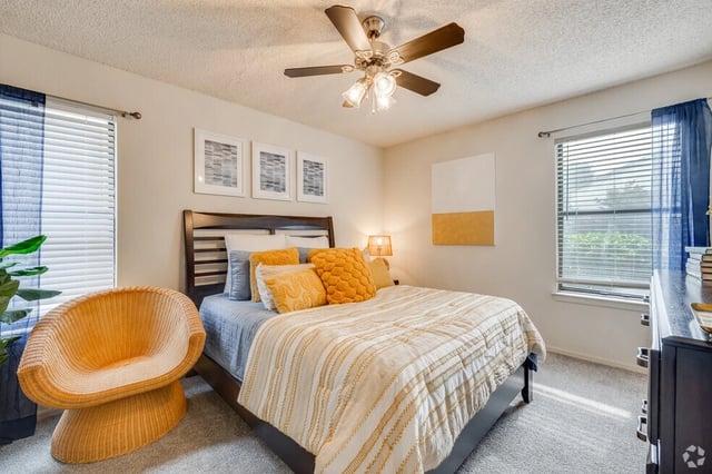 Bedroom with a queen-size bed, two side tables, a chair, and a ceiling fan.