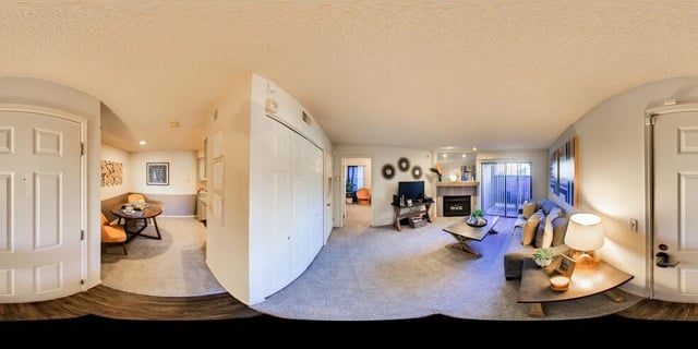 Living room and dining area of an apartment with fireplace, couch, TV, and dining table.