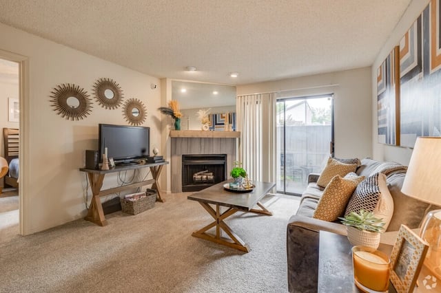 Living room with fireplace, TV, sofa, coffee table, and sliding glass door.