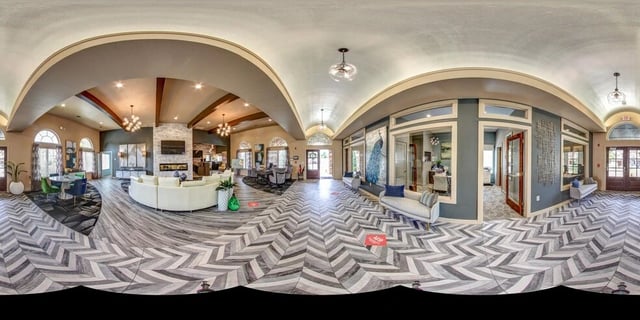 Panoramic view of apartment complex lobby with seating areas, fireplace, and reception desk.