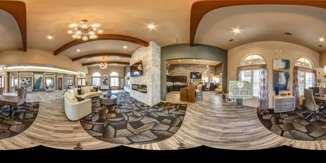 Spacious community lounge with seating areas, fireplace, kitchen, and leasing office.