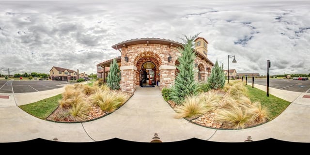 Entrance to apartment complex with stone facade and arched entryway.