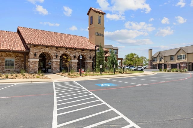 Portico apartment complex exterior with arched entryway and signage.