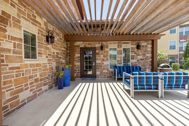 Covered patio area with stone accent walls, outdoor seating, and large planters.