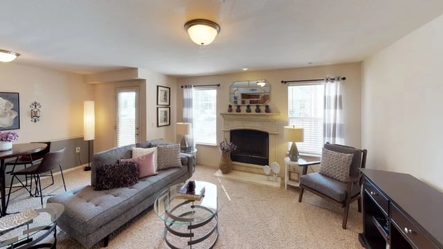 Living room with a fireplace, sofa, chaise lounge, and dining area.