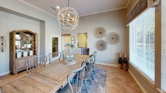 Spacious dining room with a large wooden table and chairs, a hutch, and decorative wall art.