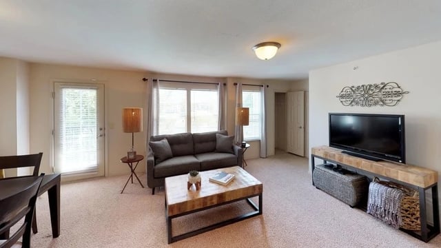 Living room with a gray sofa, coffee table, TV, and dining area.