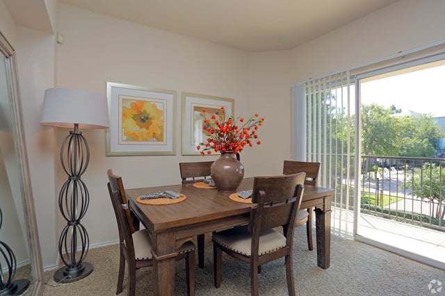 Dining room with a wooden table and chairs, a floor lamp, and artwork on the wall.