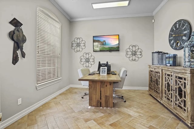 Leasing office in a community room with a wooden table, four chairs, wall art, and a mounted TV.