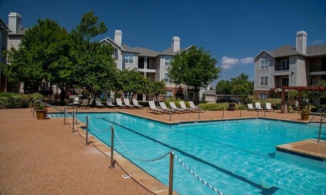 Outdoor communal pool with lounge chairs and surrounding apartment buildings.