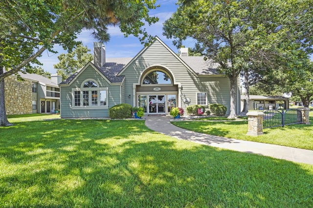 A house with a green lawn and trees in front.