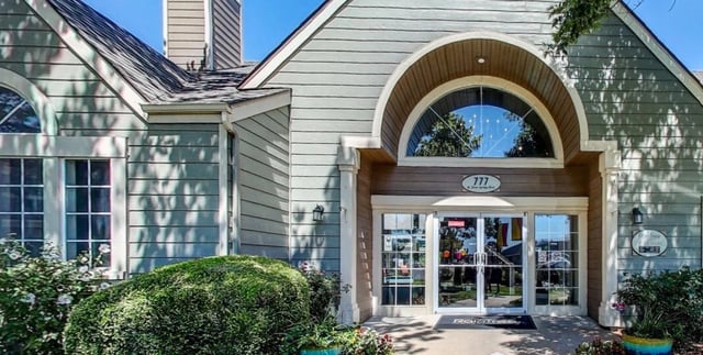 Exterior of apartment building entrance with arched window above double doors.