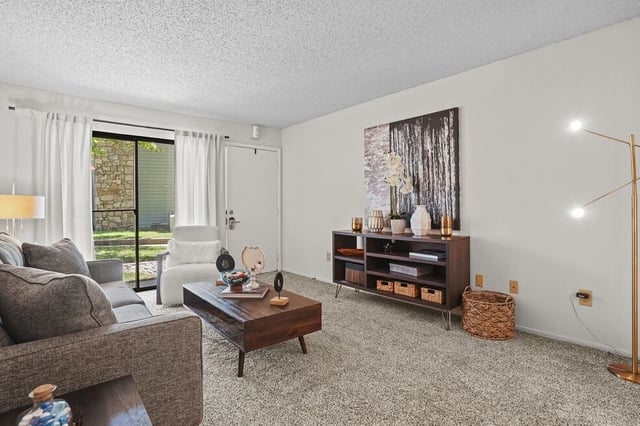Living room with sofa, coffee table, armchair, and media console.