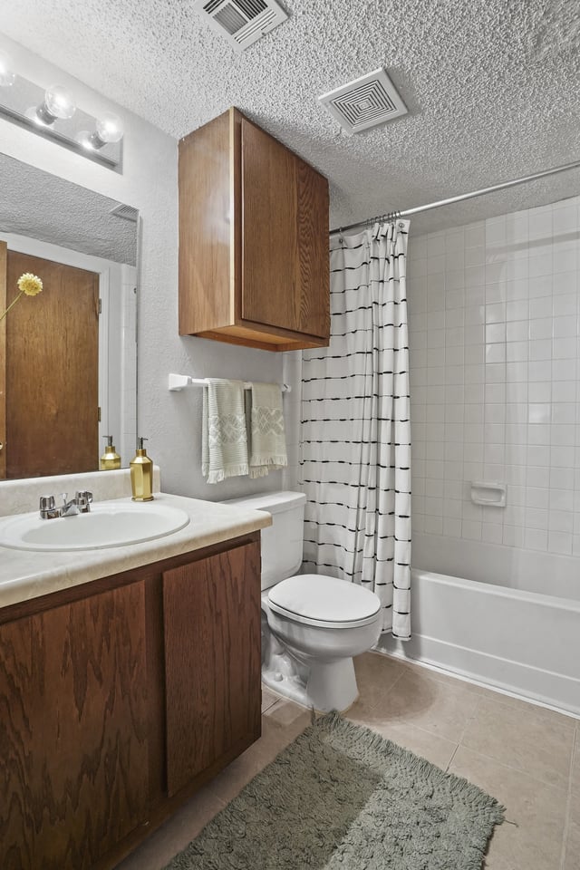 Bathroom with vanity, toilet, and bathtub with shower curtain.