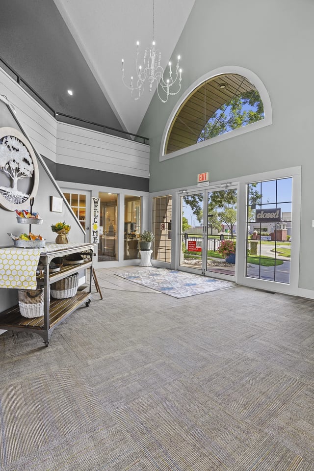 A room with a carpeted floor and a chandelier hanging from the ceiling.