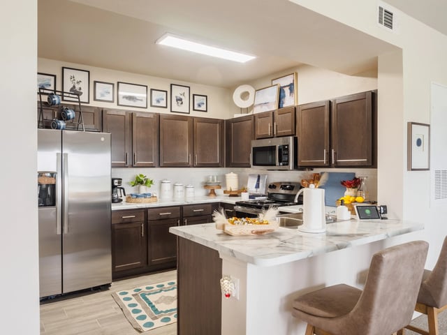 Modern kitchen with dark wood cabinets, stainless steel appliances, and a marble island.