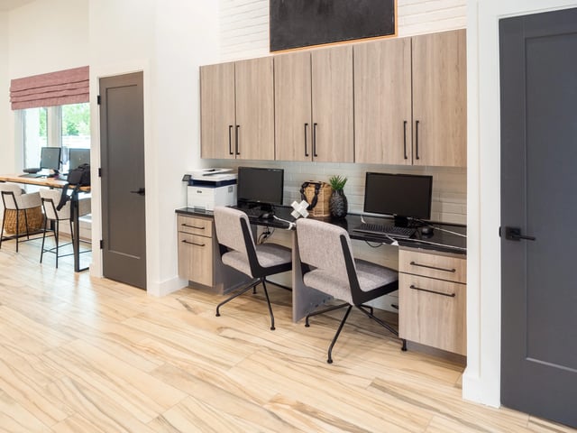 Interior of a community computer desk area with two workstations and wooden cabinets.