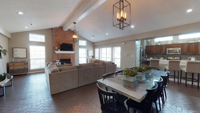 Spacious communal living area with fireplace, sectional sofa, dining table, and kitchen island.