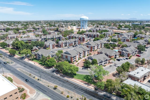 Aerial view of a sprawling apartment complex with multiple buildings, a pool, and a water tower in the background.