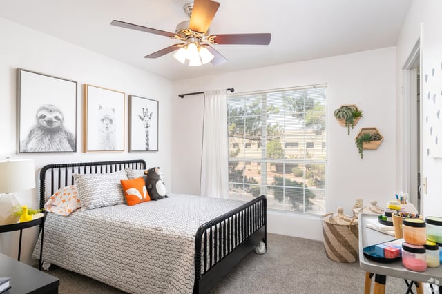 Bedroom with a queen-size bed, sloth and llama art, and a large window.