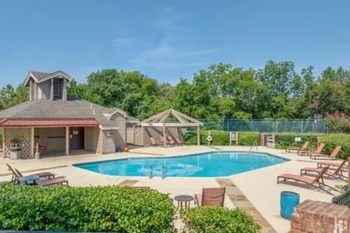 Outdoor swimming pool with lounge chairs and a covered cabana area.