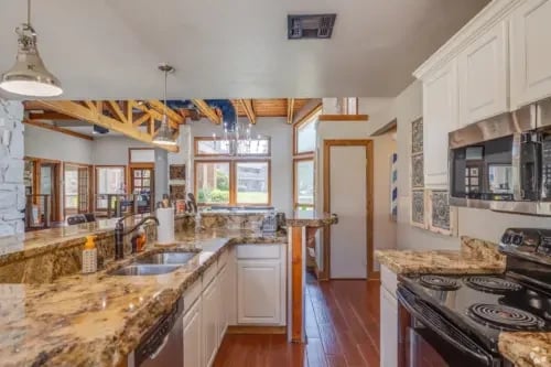 Granite countertops and stainless steel appliances in a spacious kitchen.