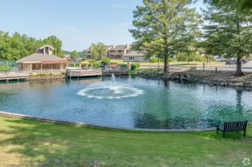A serene pond with a fountain and surrounding greenery at a multifamily property.