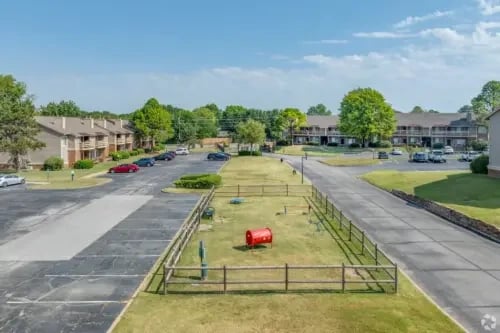 Exterior view of apartment buildings with a dog park area.