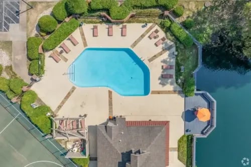 Aerial view of a swimming pool with lounge chairs and a deck overlooking a lake.