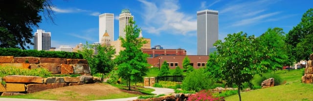 Park-like landscaped grounds with trees and a city skyline in the background