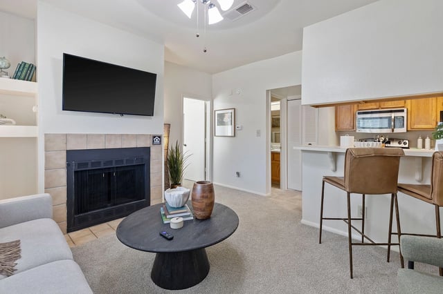 Bright living room with stone fireplace, large windows, and exposed wooden beams.