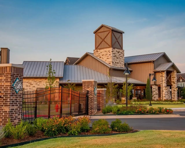 Exterior view of a gated apartment community entrance with brick columns, stone accents, and landscaped grounds.