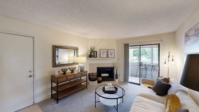 Living room with a fireplace, sofa, coffee table, and balcony access.