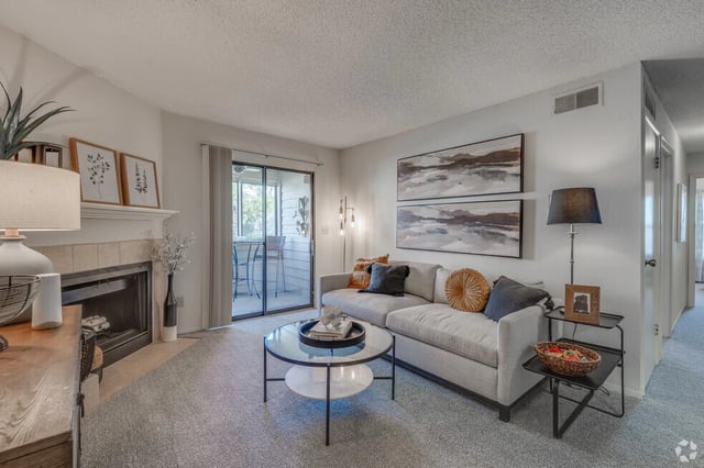 Modern living room with a fireplace, sofa, coffee table, and patio access.