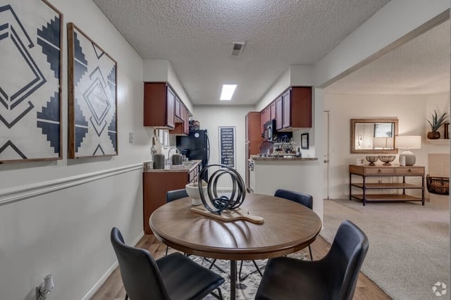 Dining area and kitchen with dark wood cabinets, granite countertops, and a round table with chairs.