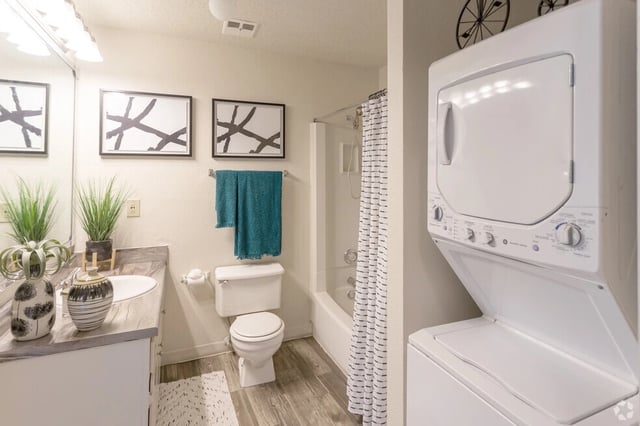Bathroom with vanity, toilet, shower/tub combo, and stackable washer/dryer.