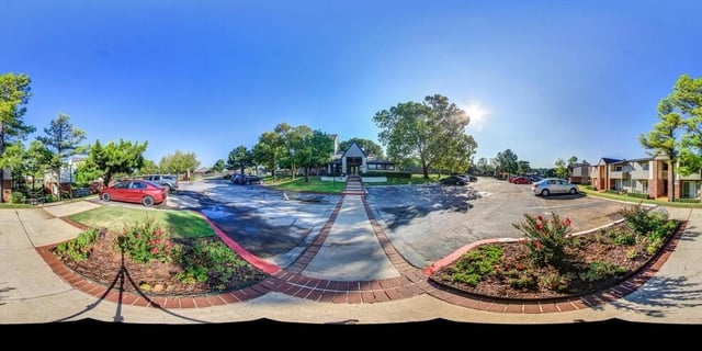 Exterior view of apartment buildings with parking lot and landscaped areas.