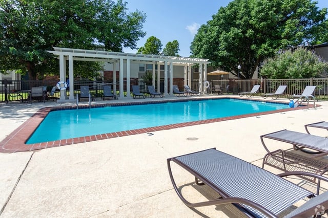 Resort-style outdoor swimming pool with lounge chairs and a pergola.