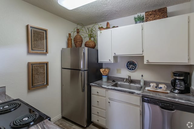 Kitchen with stainless steel refrigerator, white cabinets, and a black stovetop.