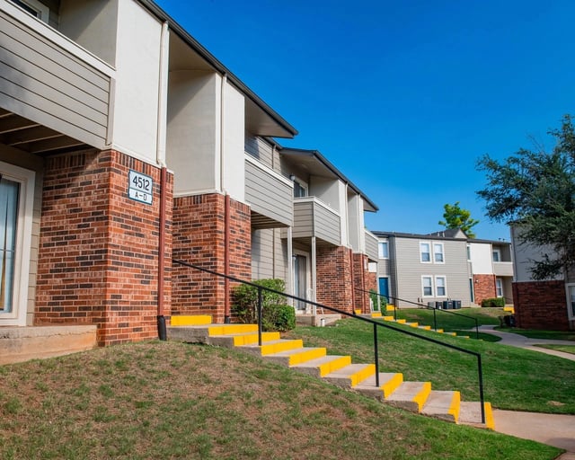 Exterior view of brick apartment buildings with yellow-edged stairs and railings.