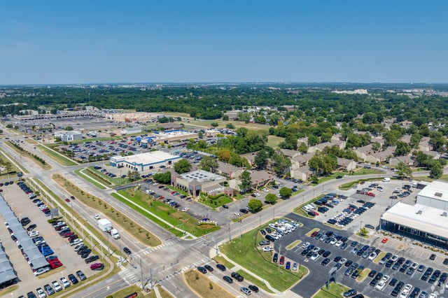 Aerial view of a large apartment community with nearby shopping centers and streets.