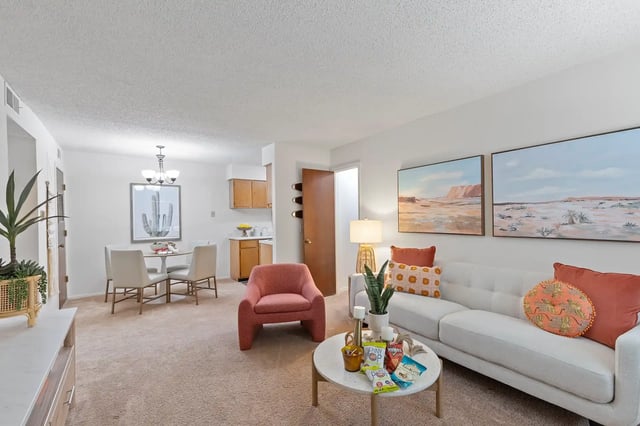 Bright and airy living room with a white couch, accent chairs, and a dining area.