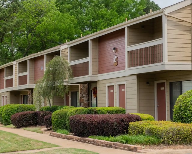Exterior view of a two-story apartment building with balconies and landscaped shrubbery.