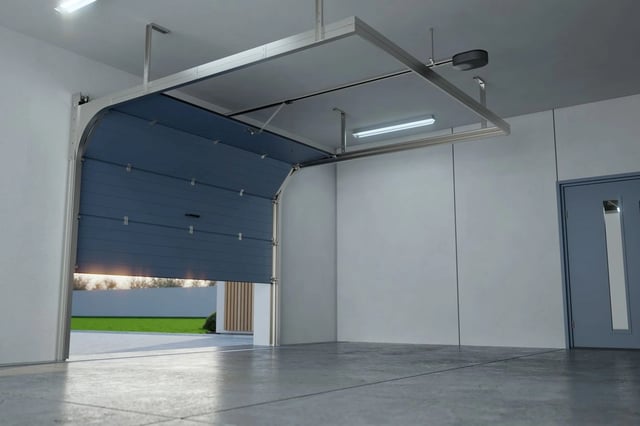 Indoor residential garage with a blue sectional door, concrete floor, and a view of green outdoors.