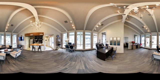 Reception area and lounge with a coffee bar, seating areas, and desks overlooking the outdoor pool area.