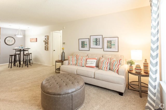 Living room with a sofa, ottoman, and dining area.